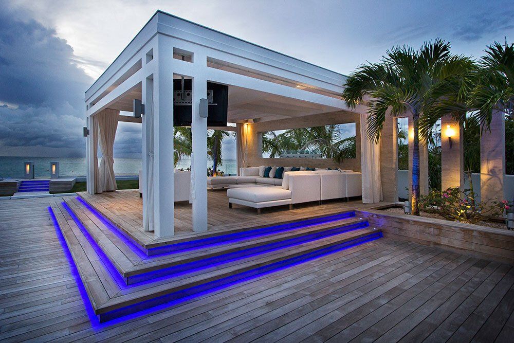 A large white house with a wooden deck and stairs leading up to it.