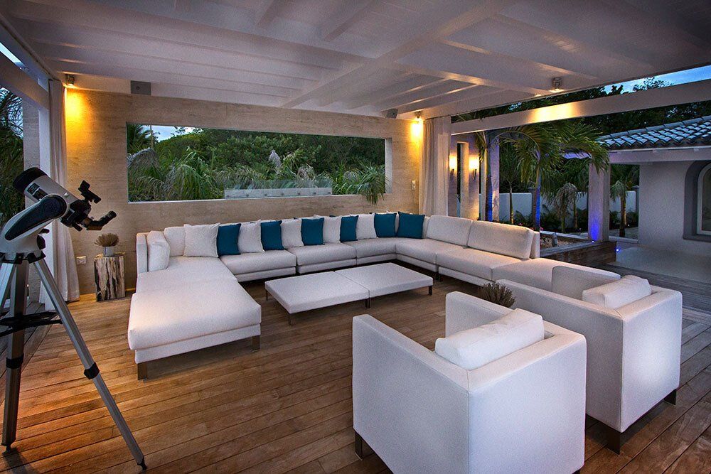 A living room with a large sectional couch and chairs and a telescope