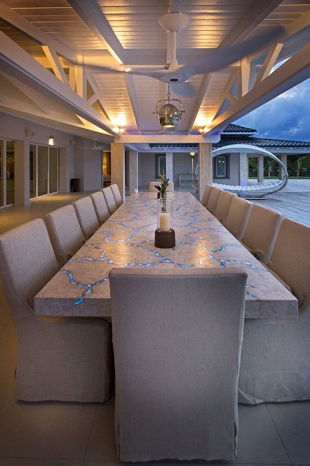 A long dining table with chairs under a covered patio.