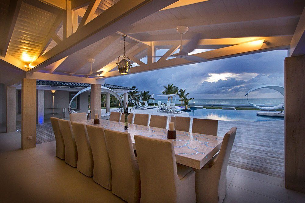 A dining room with a long table and chairs and a view of the ocean.