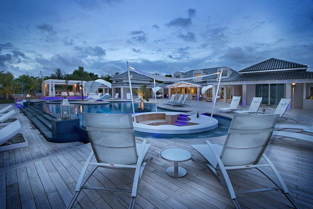 A couple of chairs sitting on top of a wooden deck next to a swimming pool.