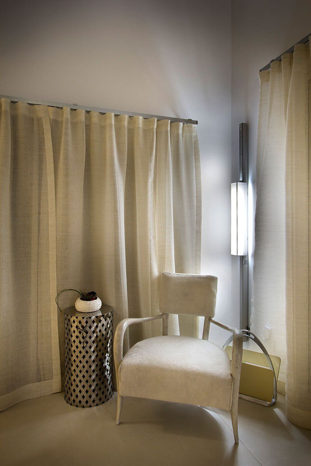A chair and a stool in a room with curtains