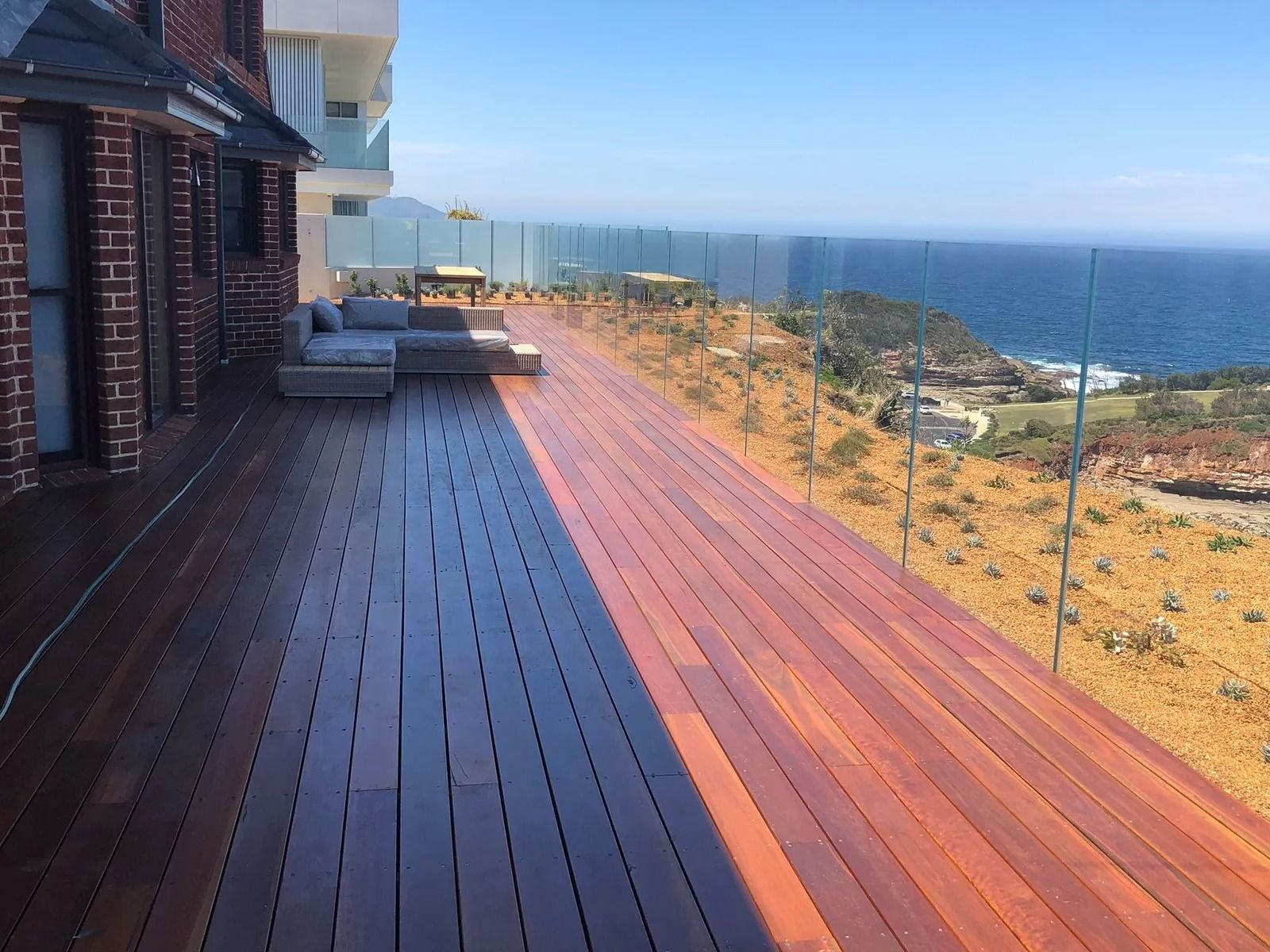 Wooden Deck Overlooking the Ocean With Glass Railing — Divine Landscape Creations in Berkeley Vale, NSW