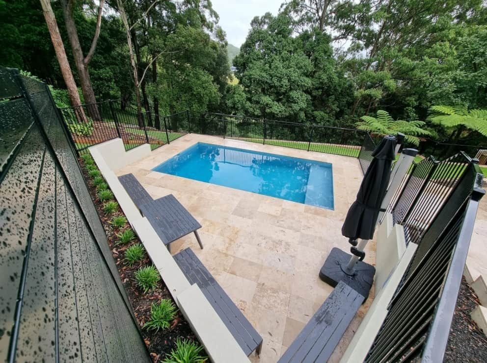Pool With Blue Water Surrounded by Stone Patio — Divine Landscape Creations in Tuggerah, NSW