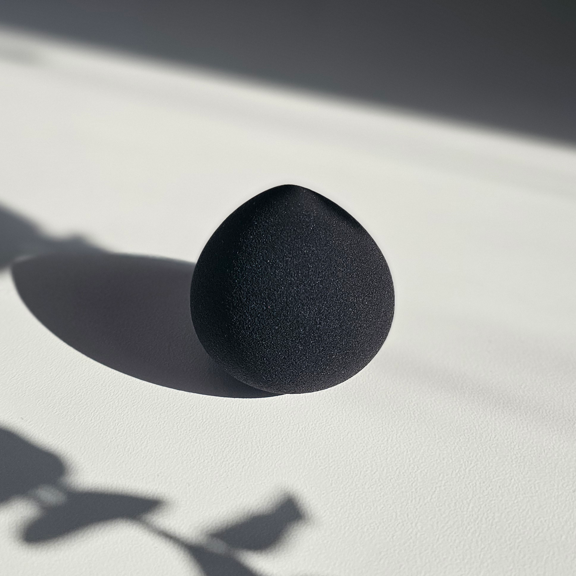 A black sponge is sitting on a white surface.