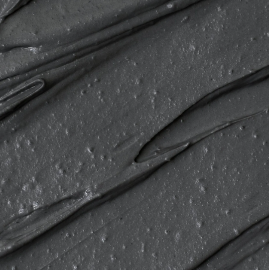 A close up of a black clay mask on a white background.