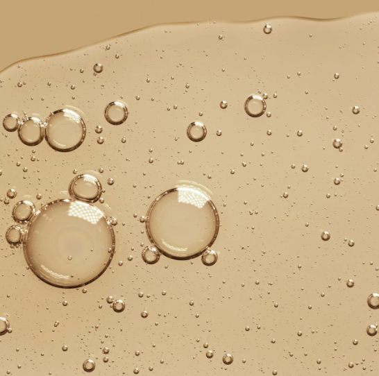 A close up of bubbles in a liquid on a brown surface.