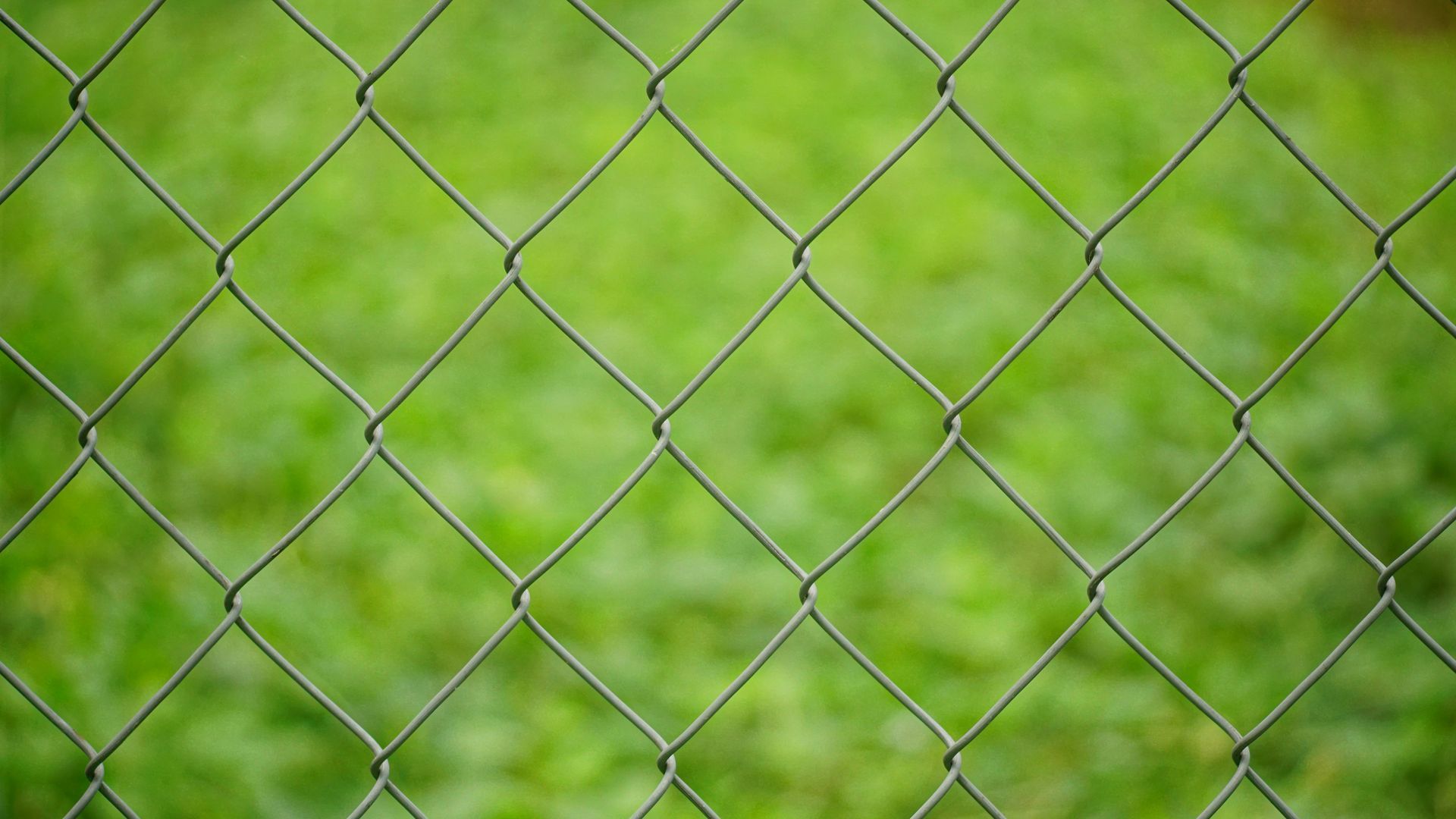 A long chain link fence with barbed wire stretches into istance 