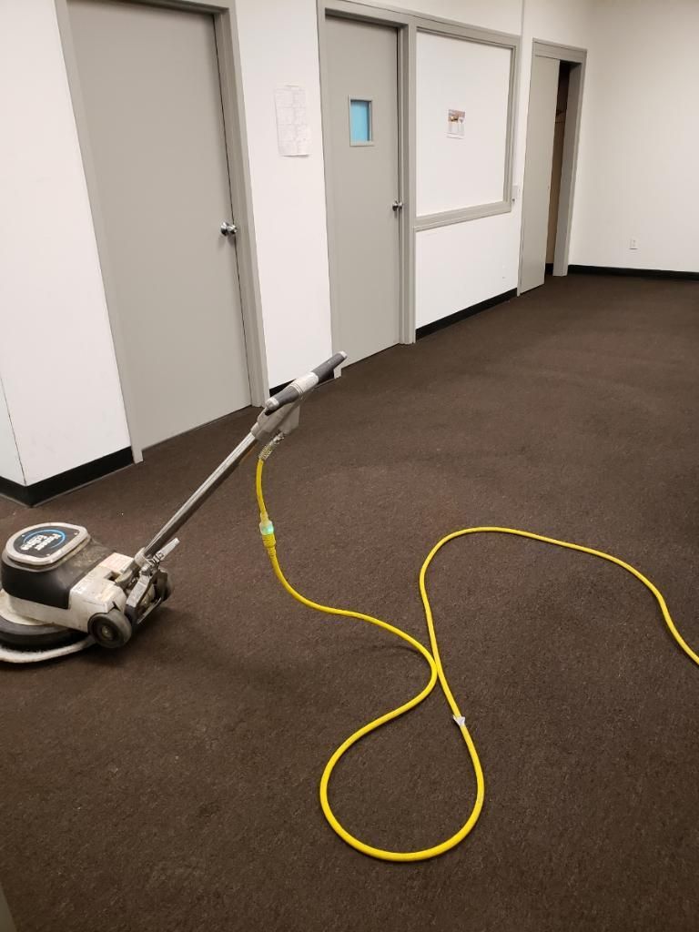 A vacuum cleaner is sitting on a brown carpet in a room.
