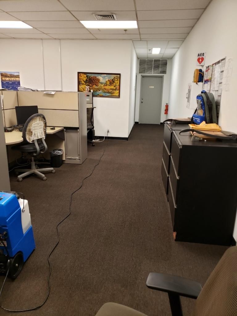 A long hallway in an office with cubicles and chairs