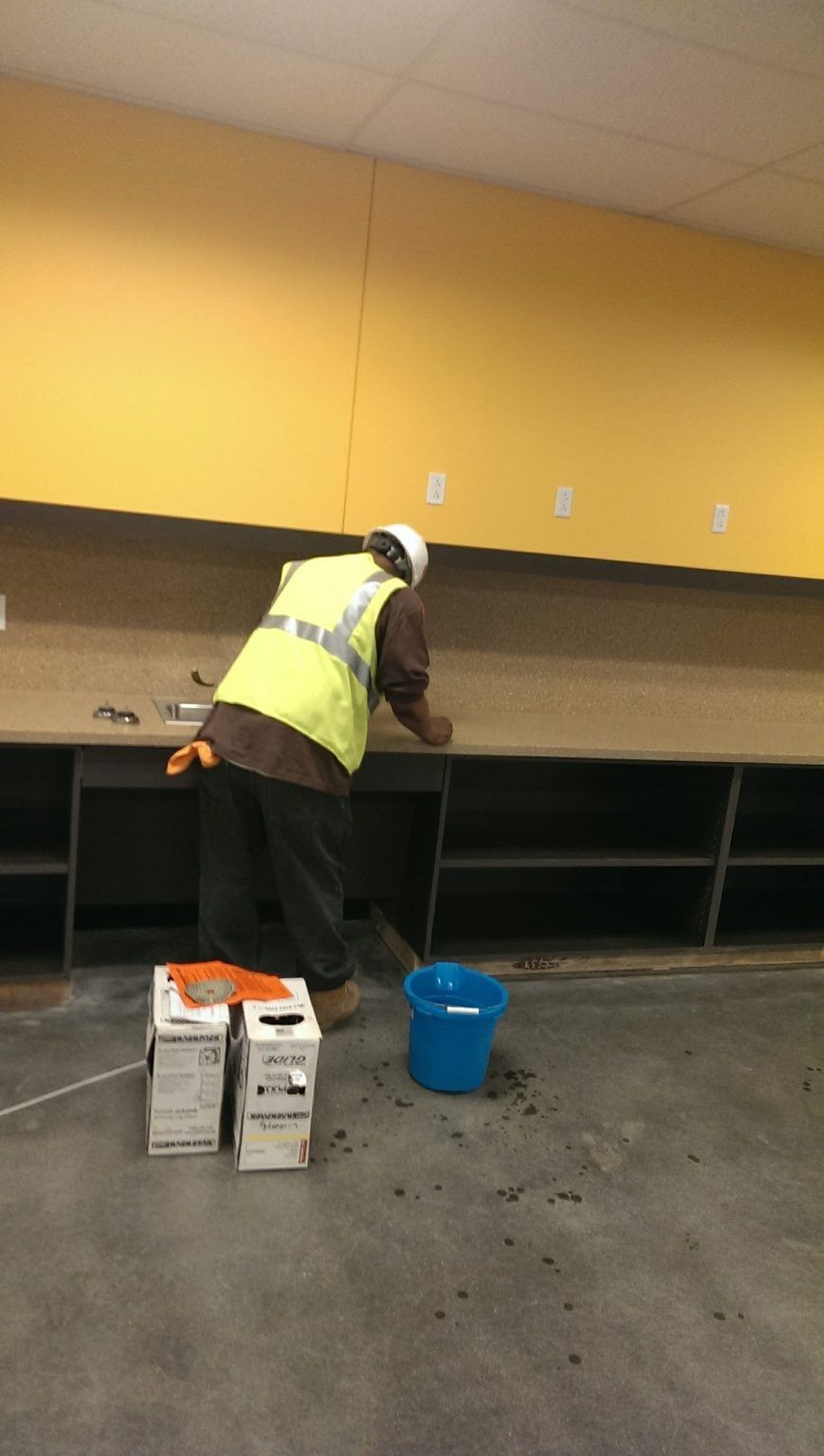 A man in a yellow vest is working on a counter