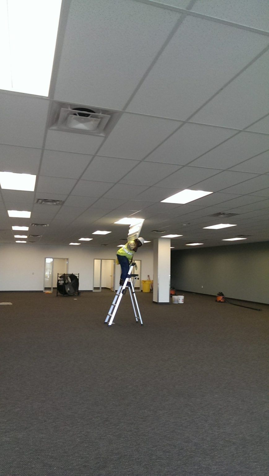A man is standing on a ladder in an empty room.