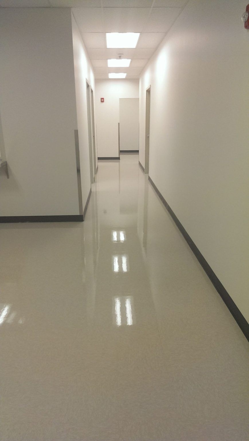A long hallway with white walls and a shiny floor