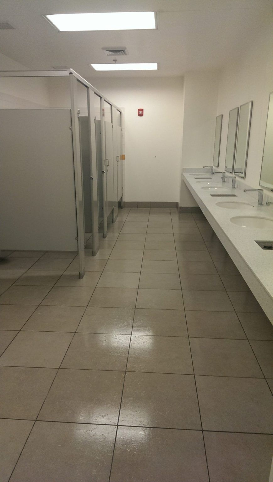 A public restroom with a lot of sinks and cubicles.