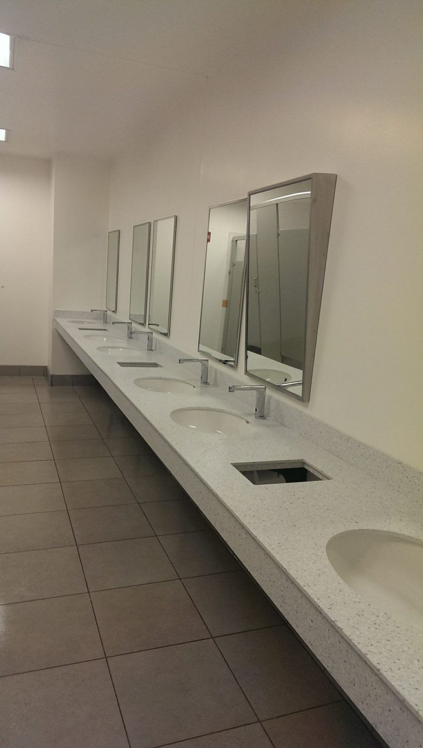 A public restroom with a long row of sinks and mirrors.