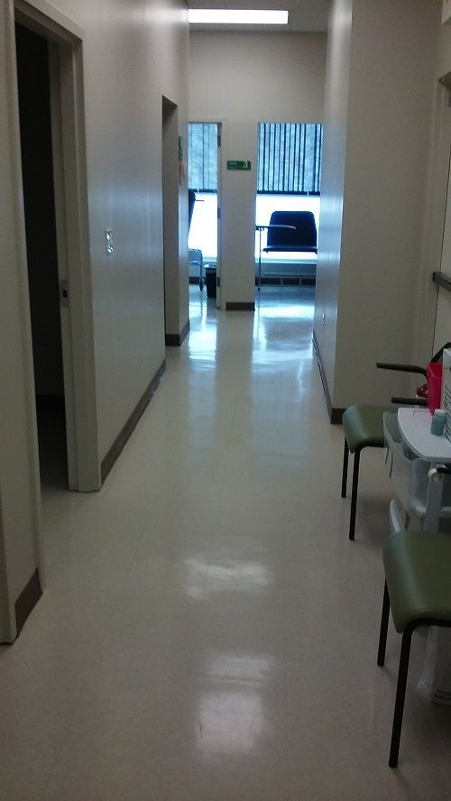 A long hallway in a hospital with chairs and tables.