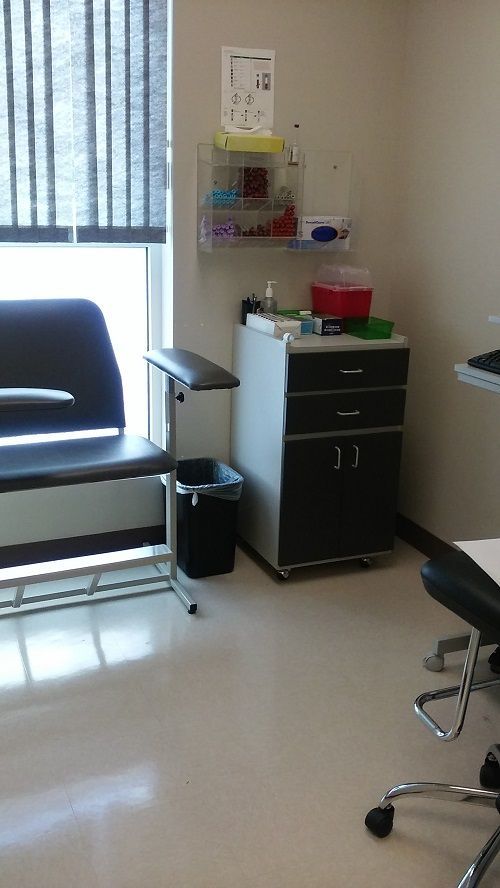 A waiting room with a chair a desk and a window