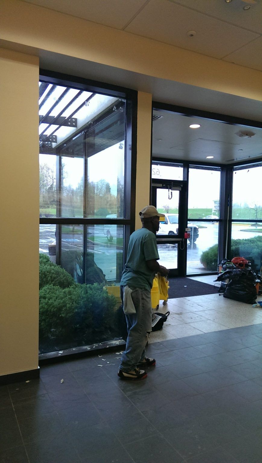A man is cleaning a building with a yellow mop.