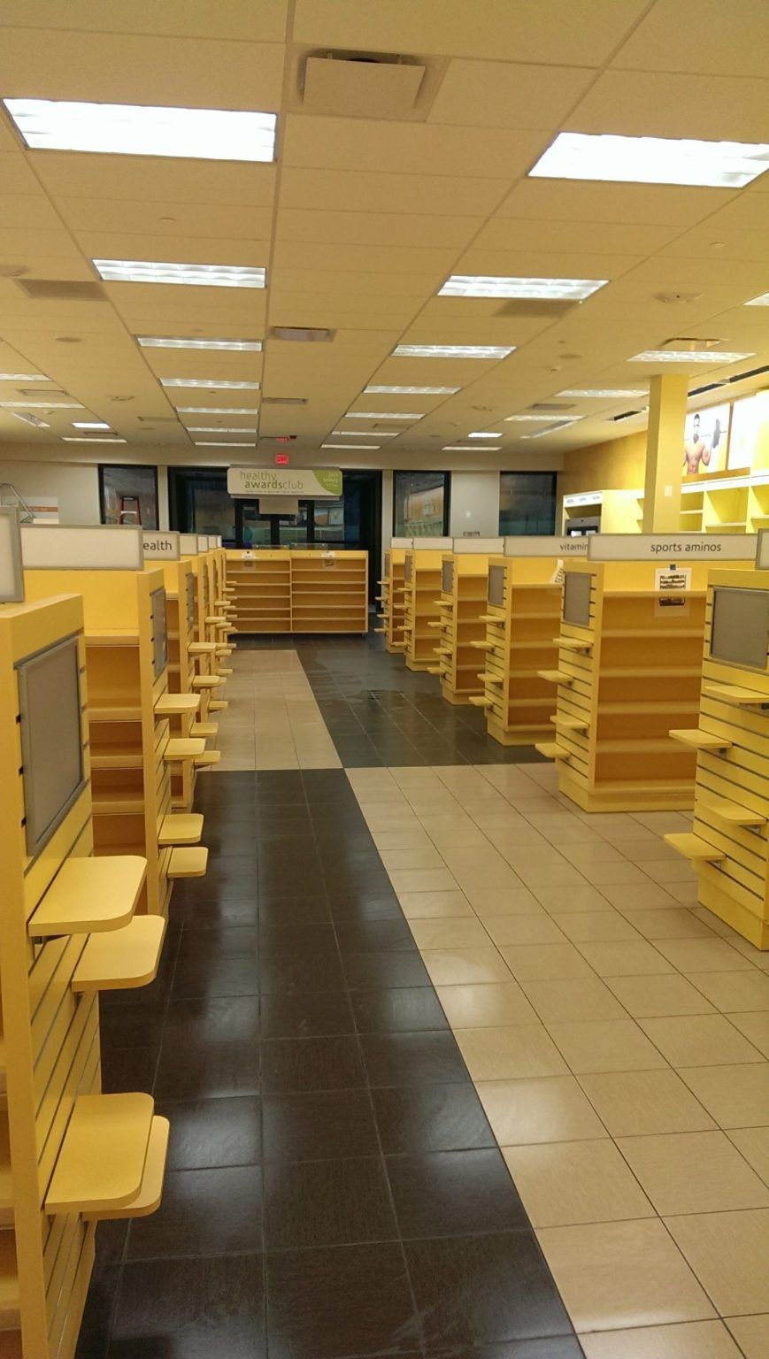 An empty store with yellow shelves and black tile floors