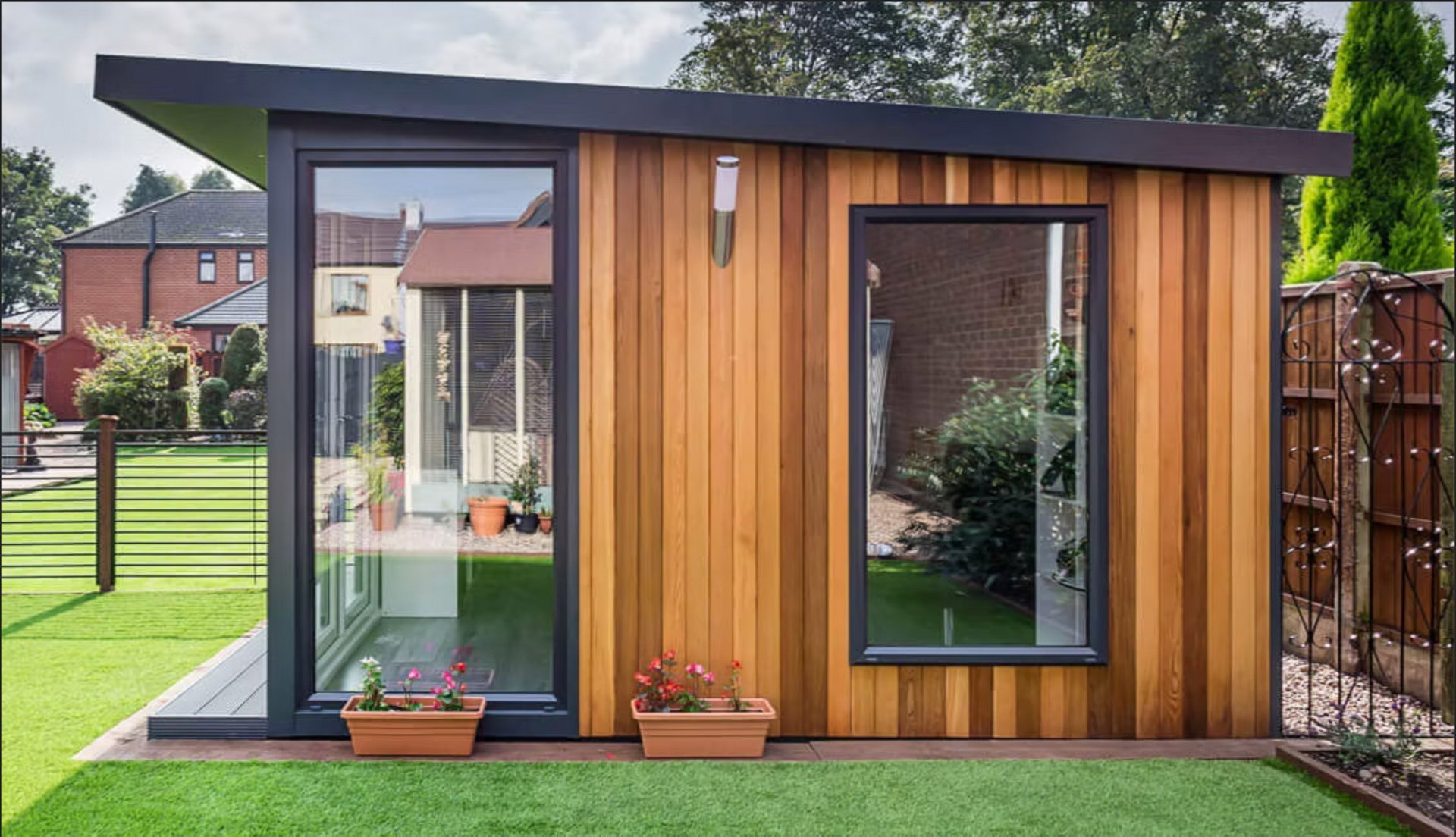 Modern wooden garden office with large windows, set on a green lawn.