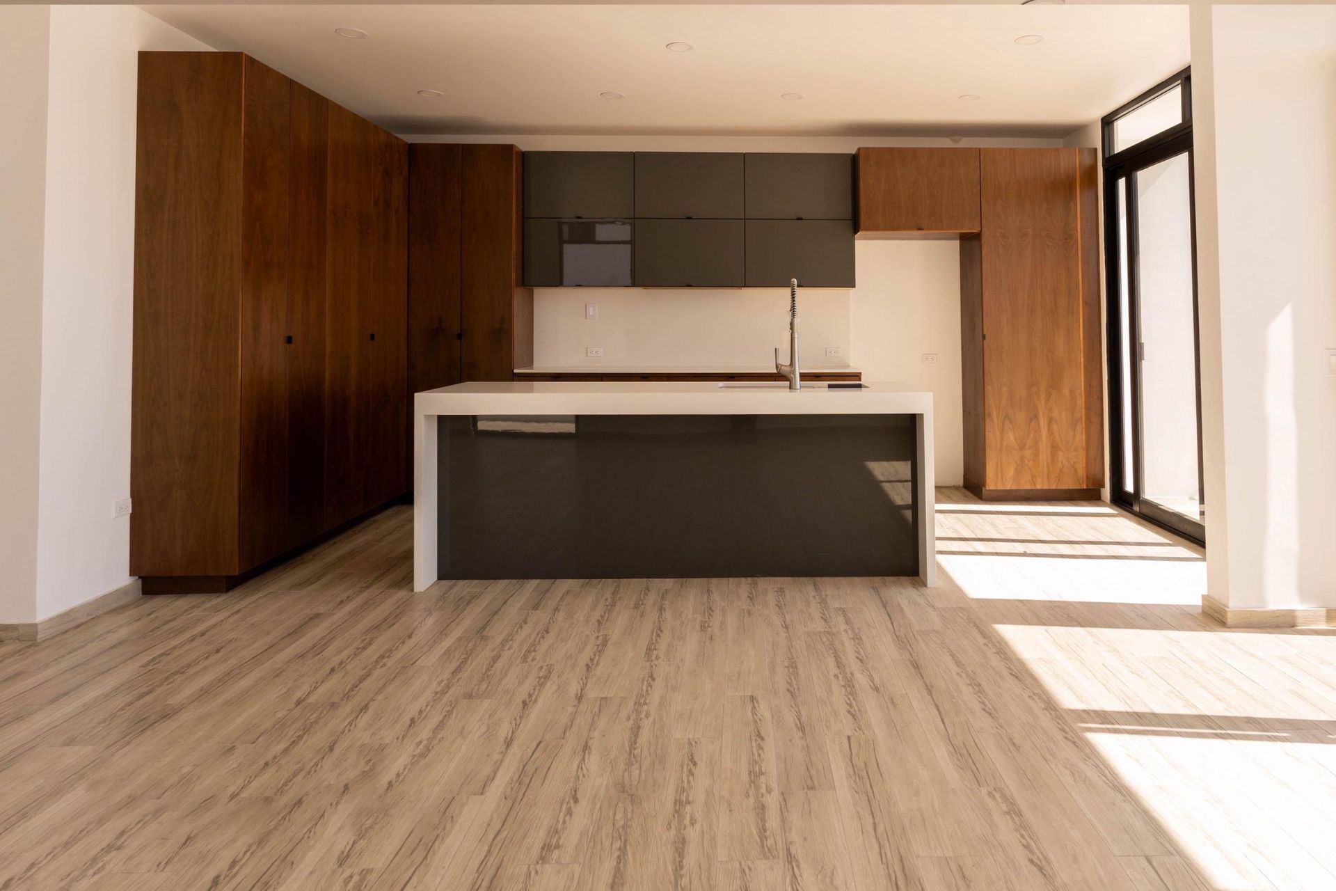 An empty kitchen with a large island in the middle of the room.