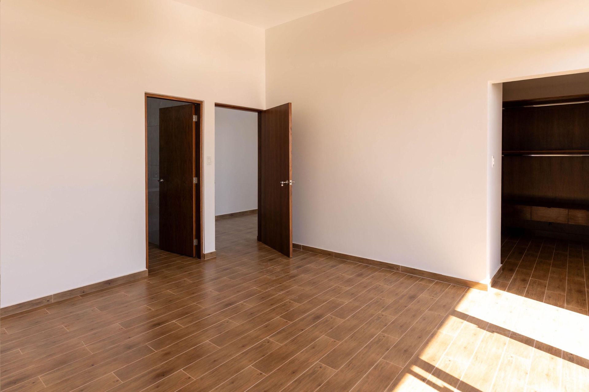 An empty room with wooden floors and white walls.