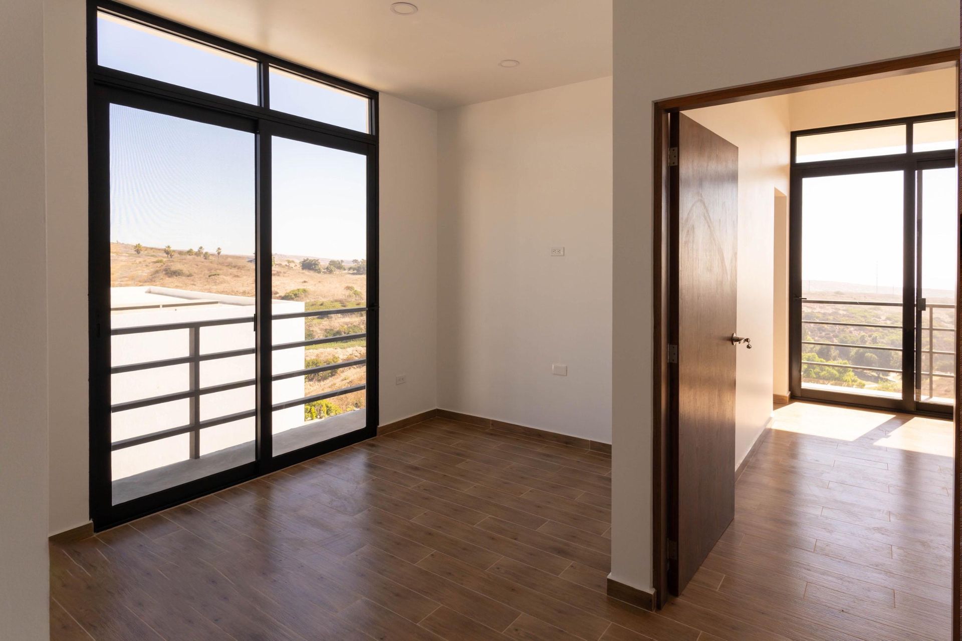 An empty room with a balcony and sliding glass doors.