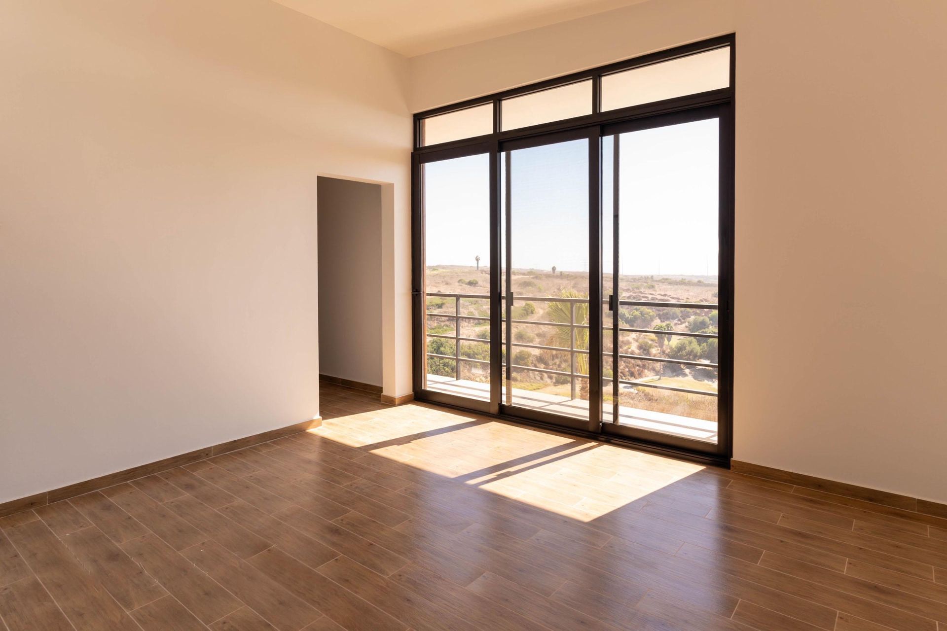 An empty room with a balcony and sliding glass doors.