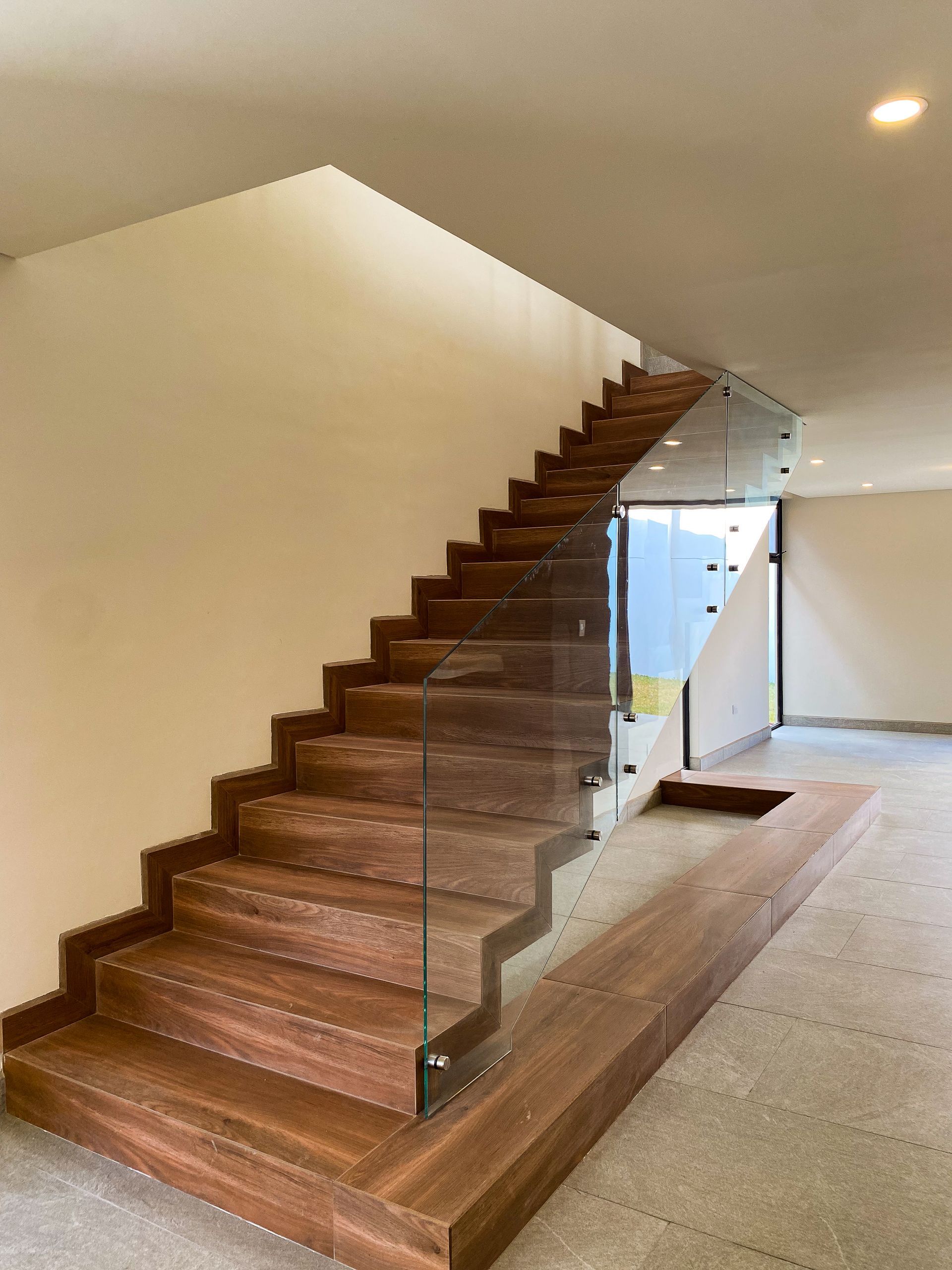 A wooden staircase with a glass railing in a house