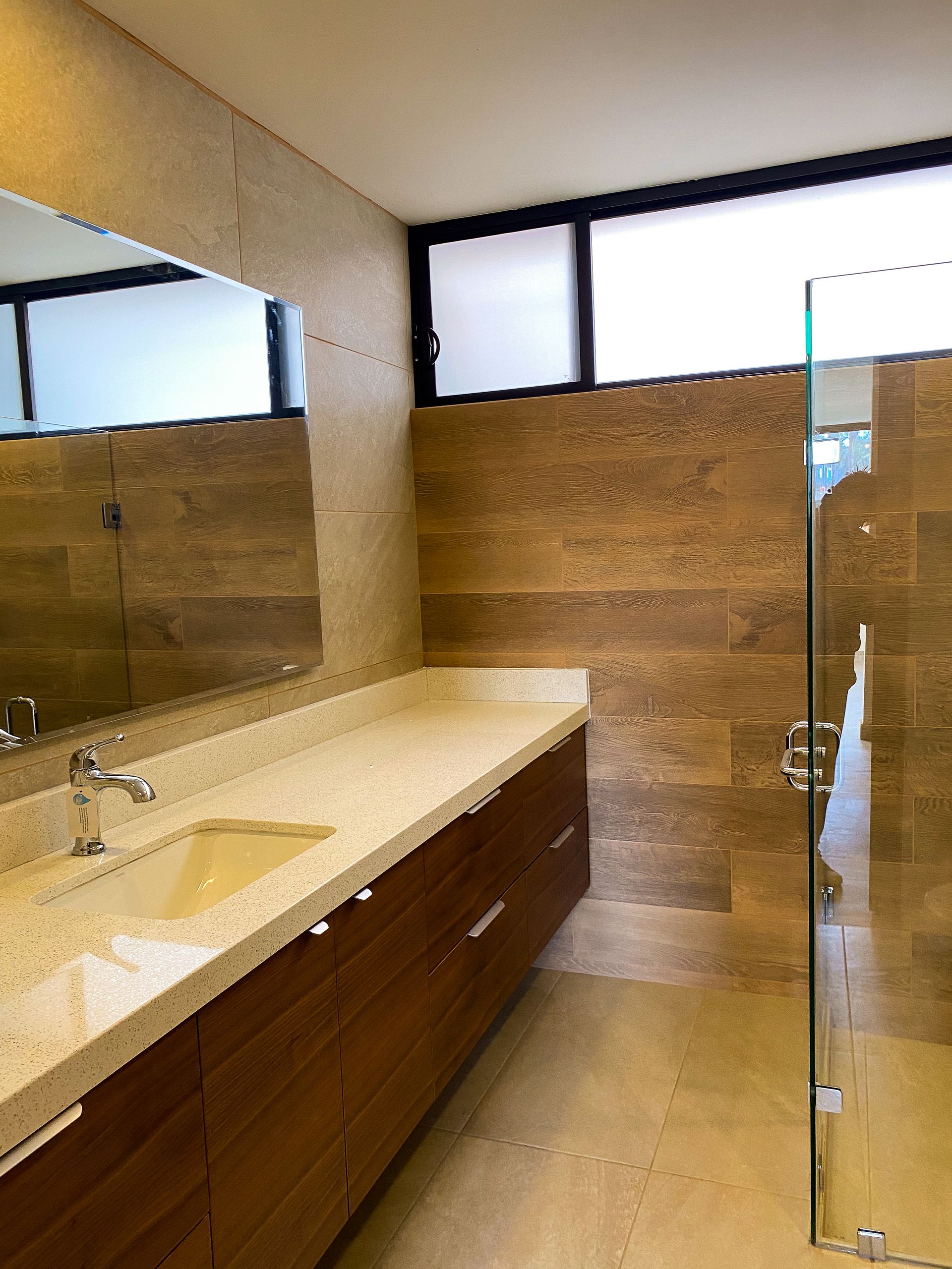 A bathroom with a sink , mirror and walk in shower.