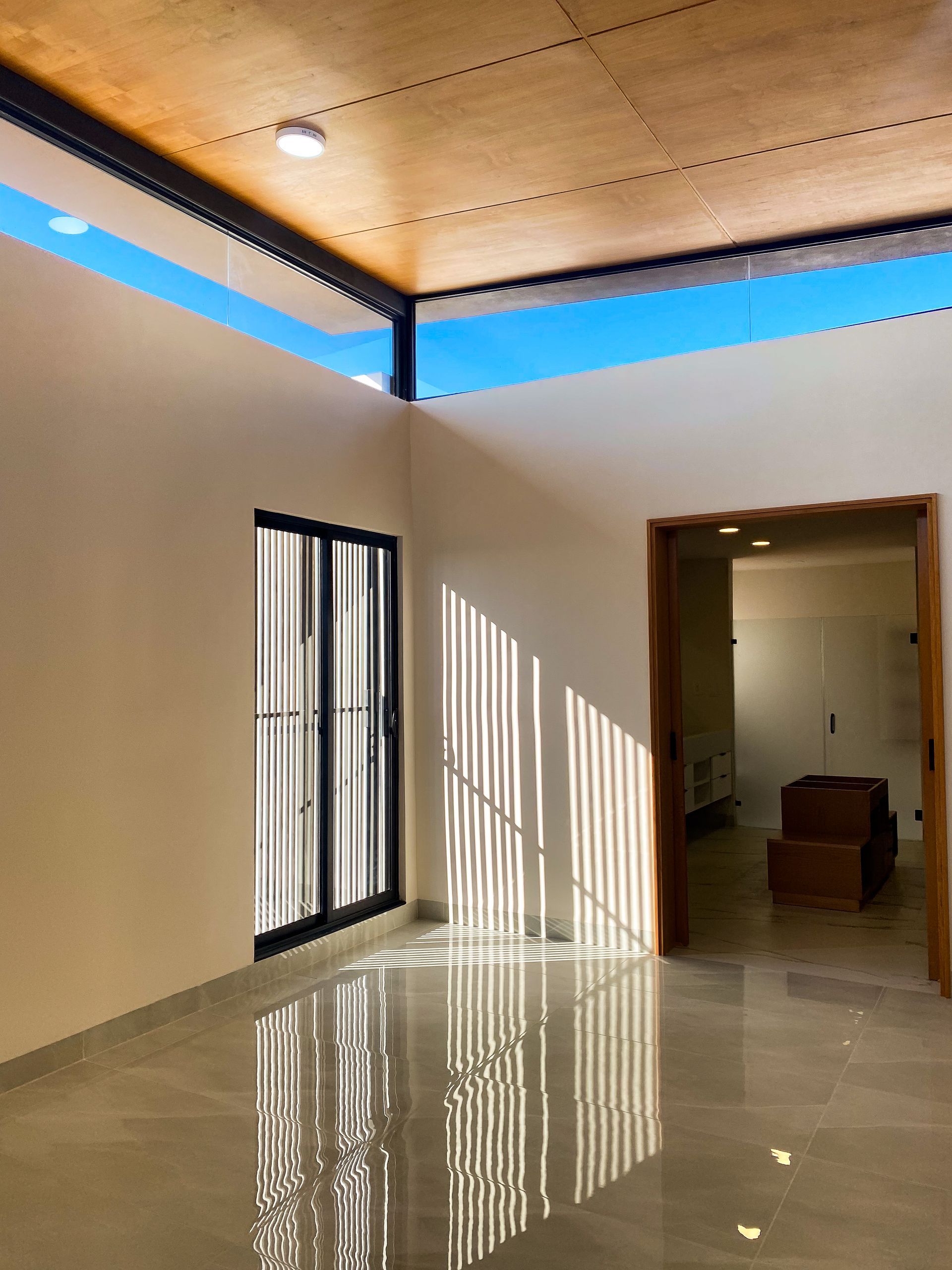 An empty room with a wooden ceiling and sliding glass doors