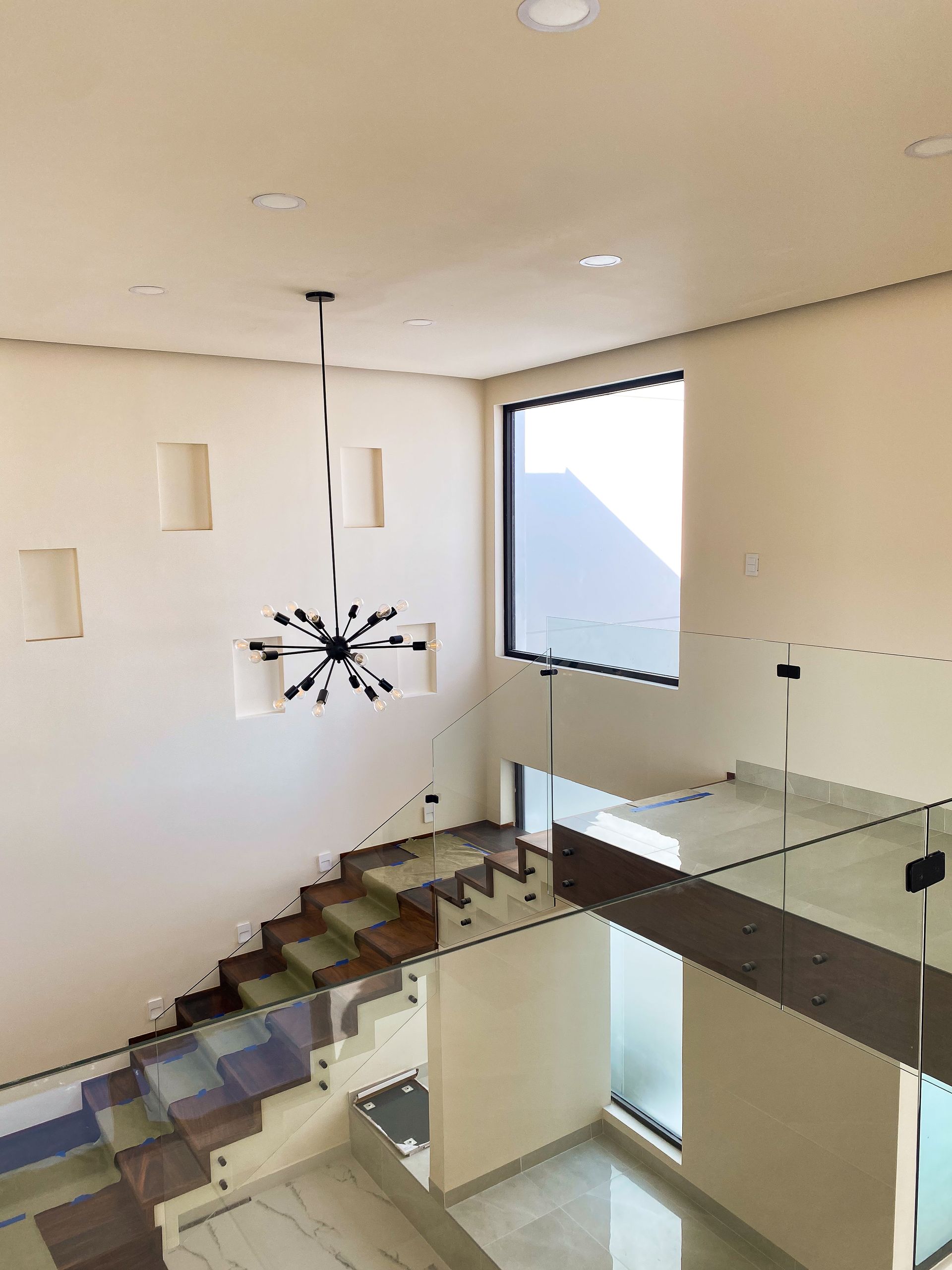 A staircase with a glass railing and a clock hanging from the ceiling.