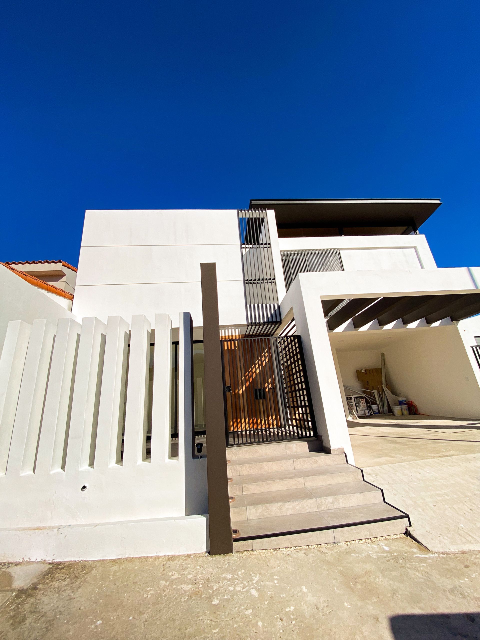 A large white house with stairs leading up to it and a blue sky in the background.