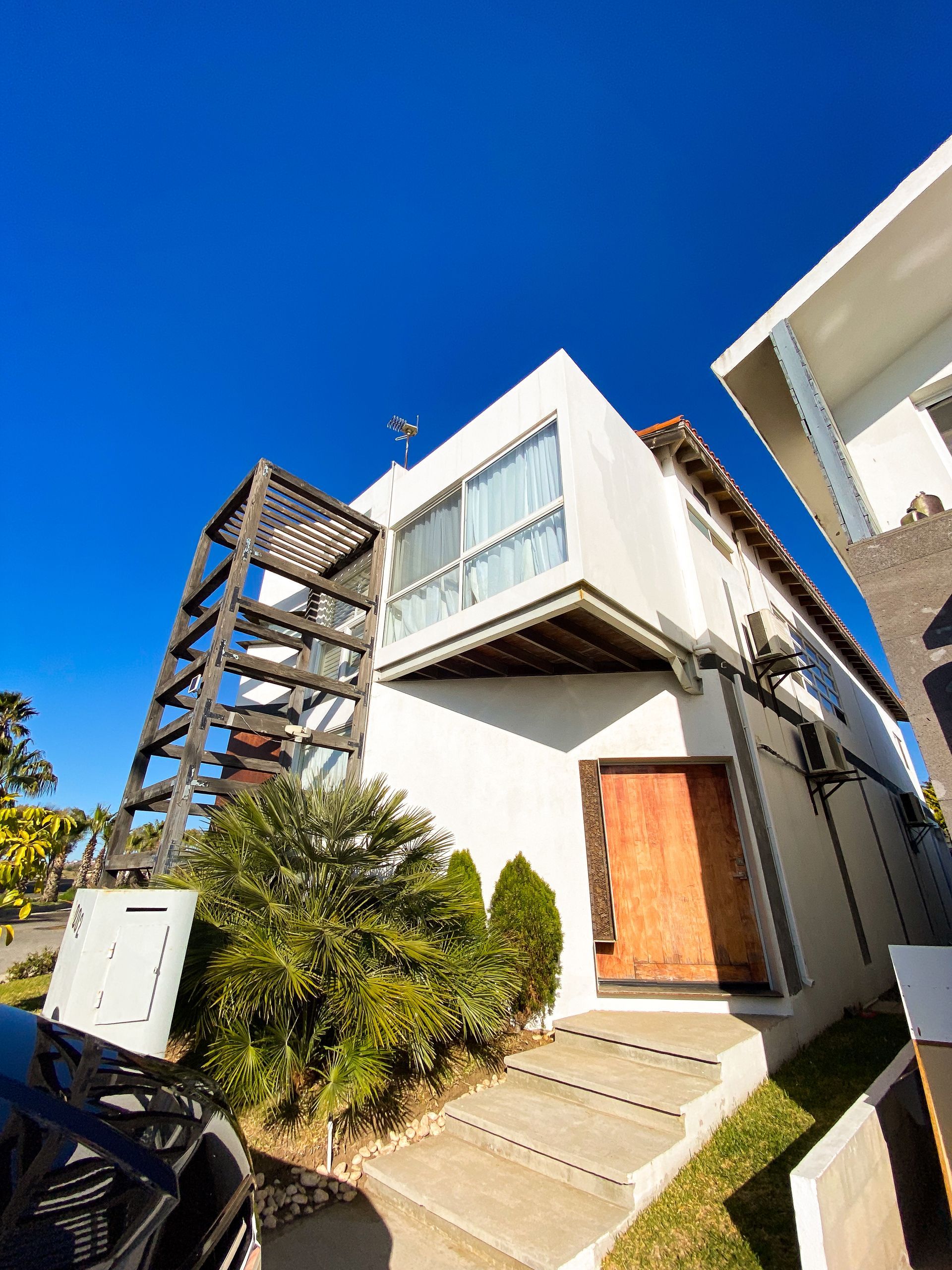 A white house with stairs leading up to it and a car parked in front of it.
