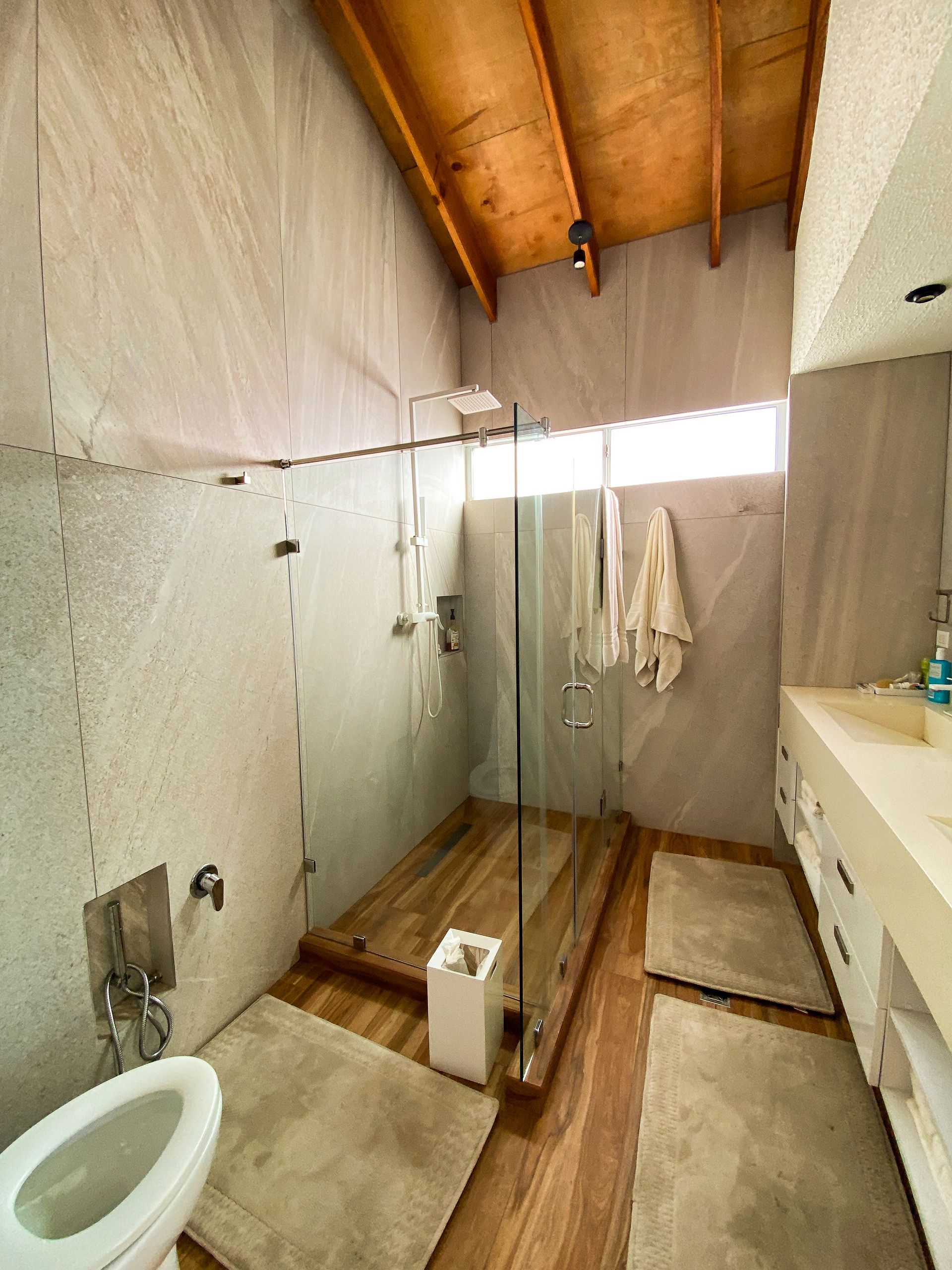A bathroom with a toilet , sink and shower.