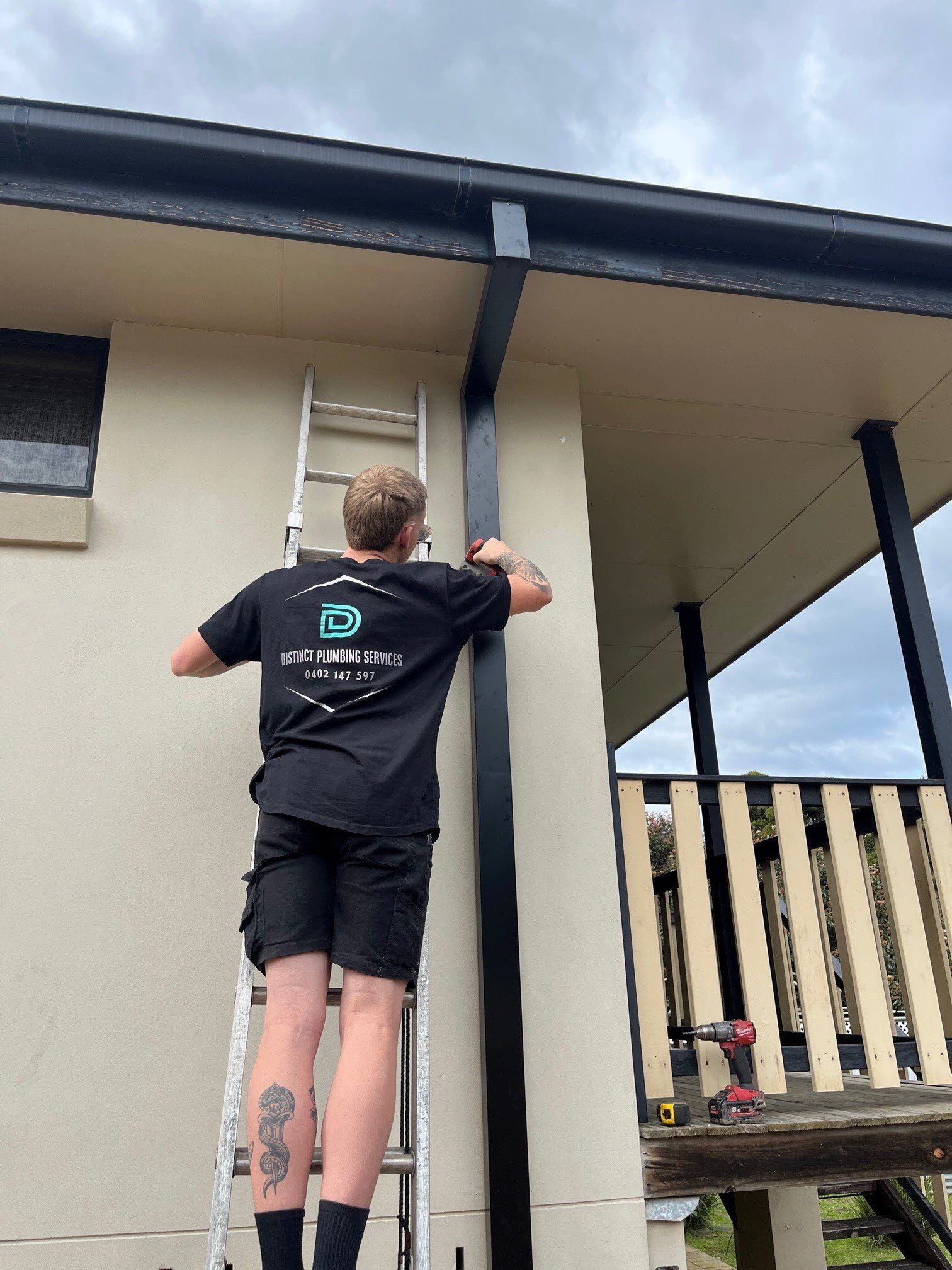 Young Plumber Working With Pipe Wrench And Tools In Kitchen — Distinct Plumbing Services In Shellharbour