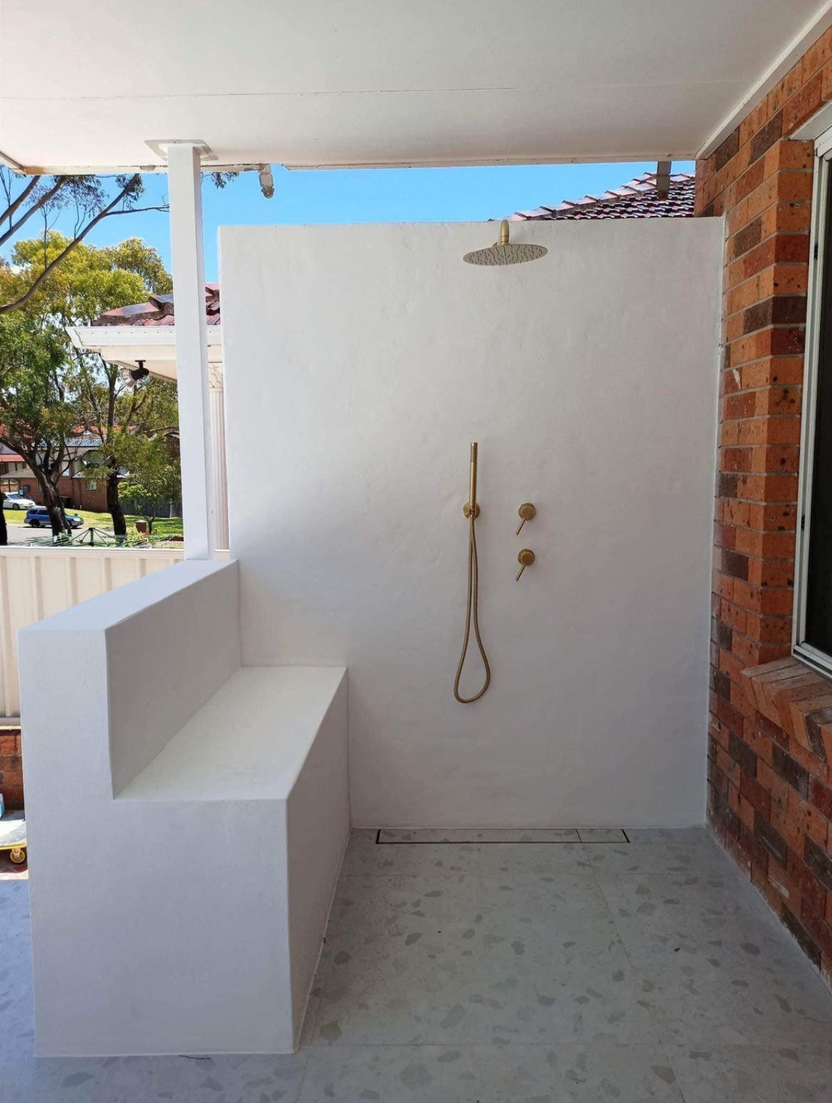 An outdoor shower with white walls and tiles — Distinct Plumbing Services In Wollongong, NSW