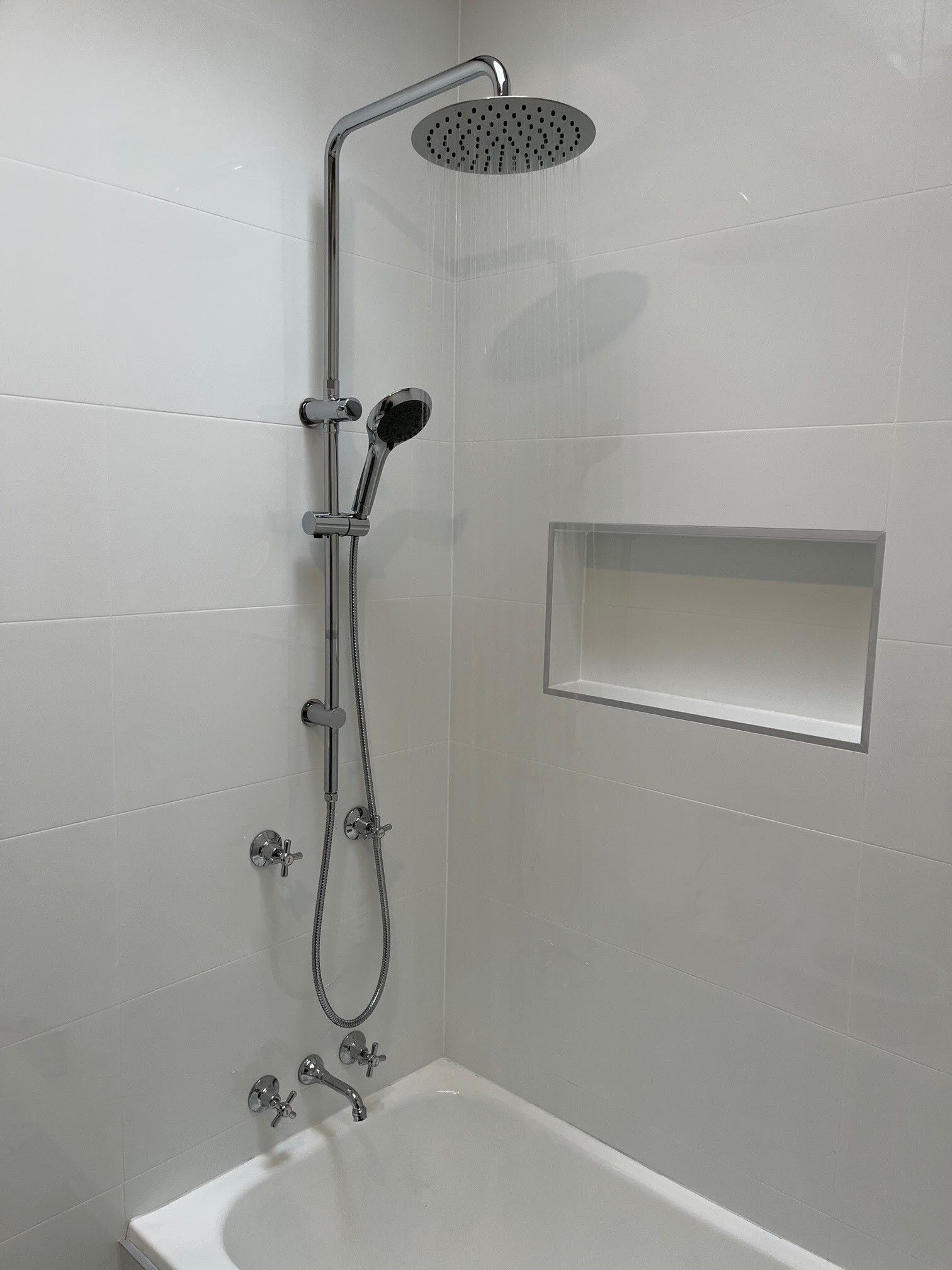 A shower and bath tub with the water running— Distinct Plumbing Services In Kiama, NSW