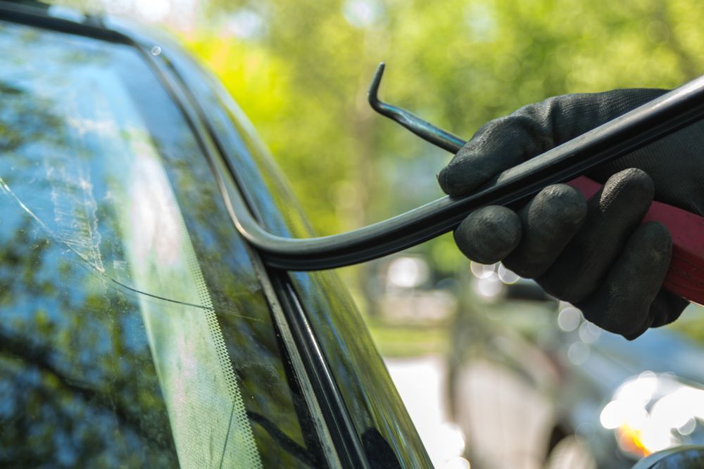 A Person is Using a Pair of Pliers to Remove a Broken Windshield From a Car — Camden Haven Panel Works In Laurieton, NSW