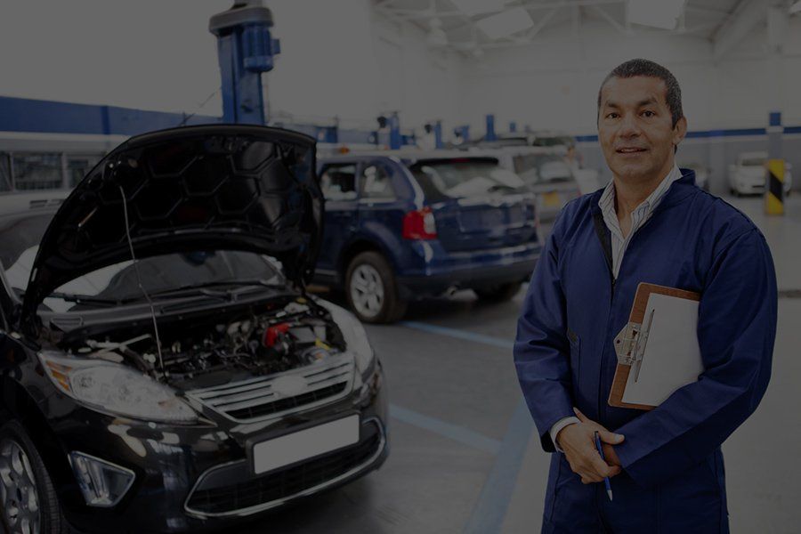 a man smiling by a car with the hood open