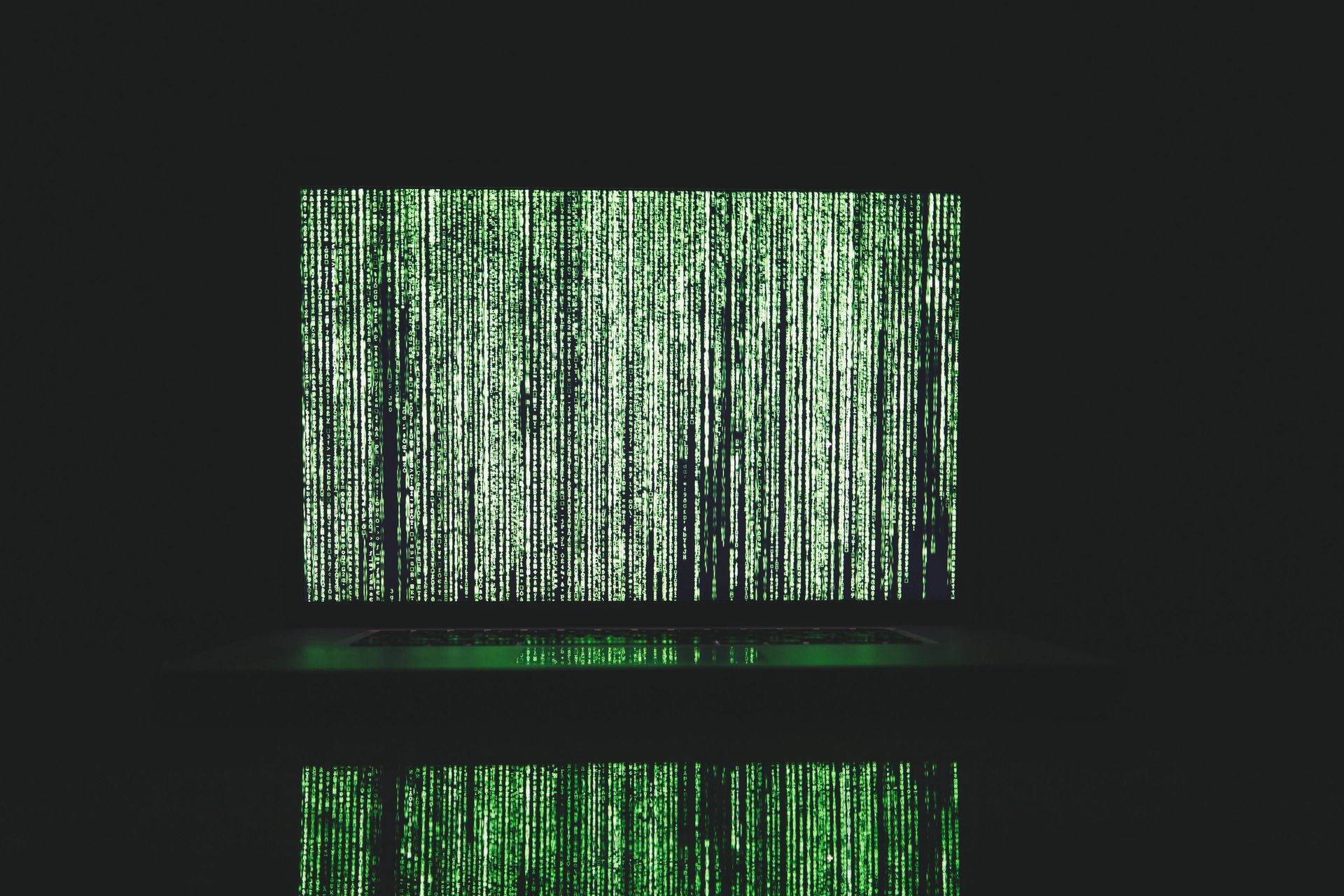 A laptop computer with green matrix code on the screen.