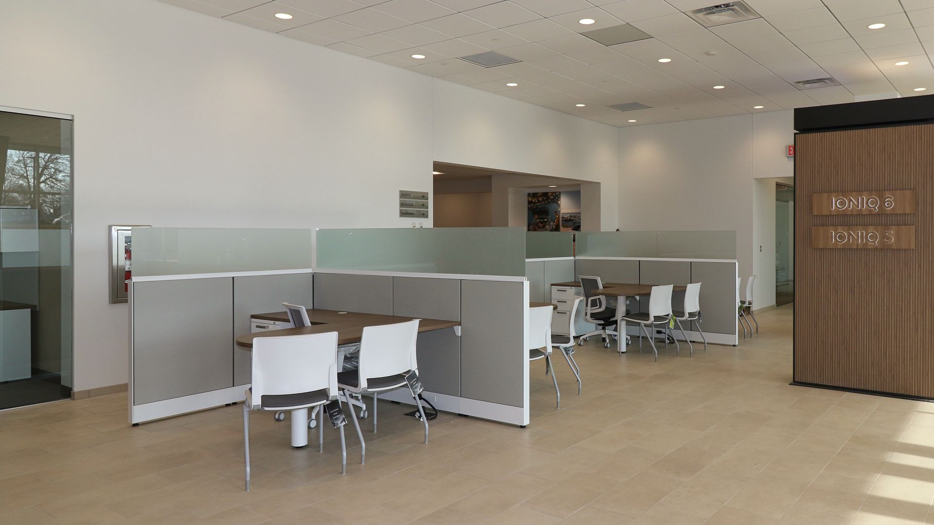 A modern office with a large desk , chairs , and a flat screen tv.