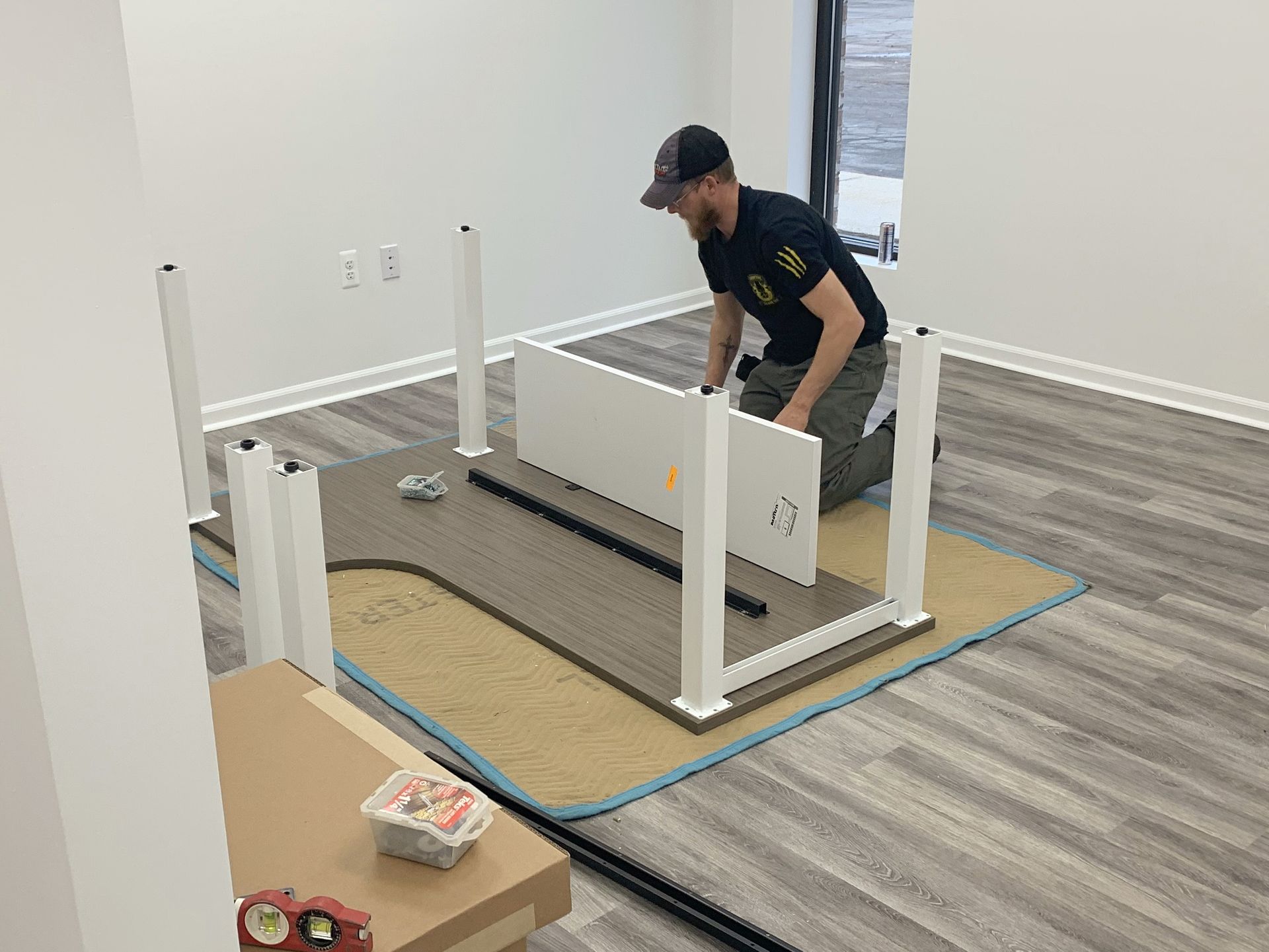 A man is kneeling down to assemble a table in a room.