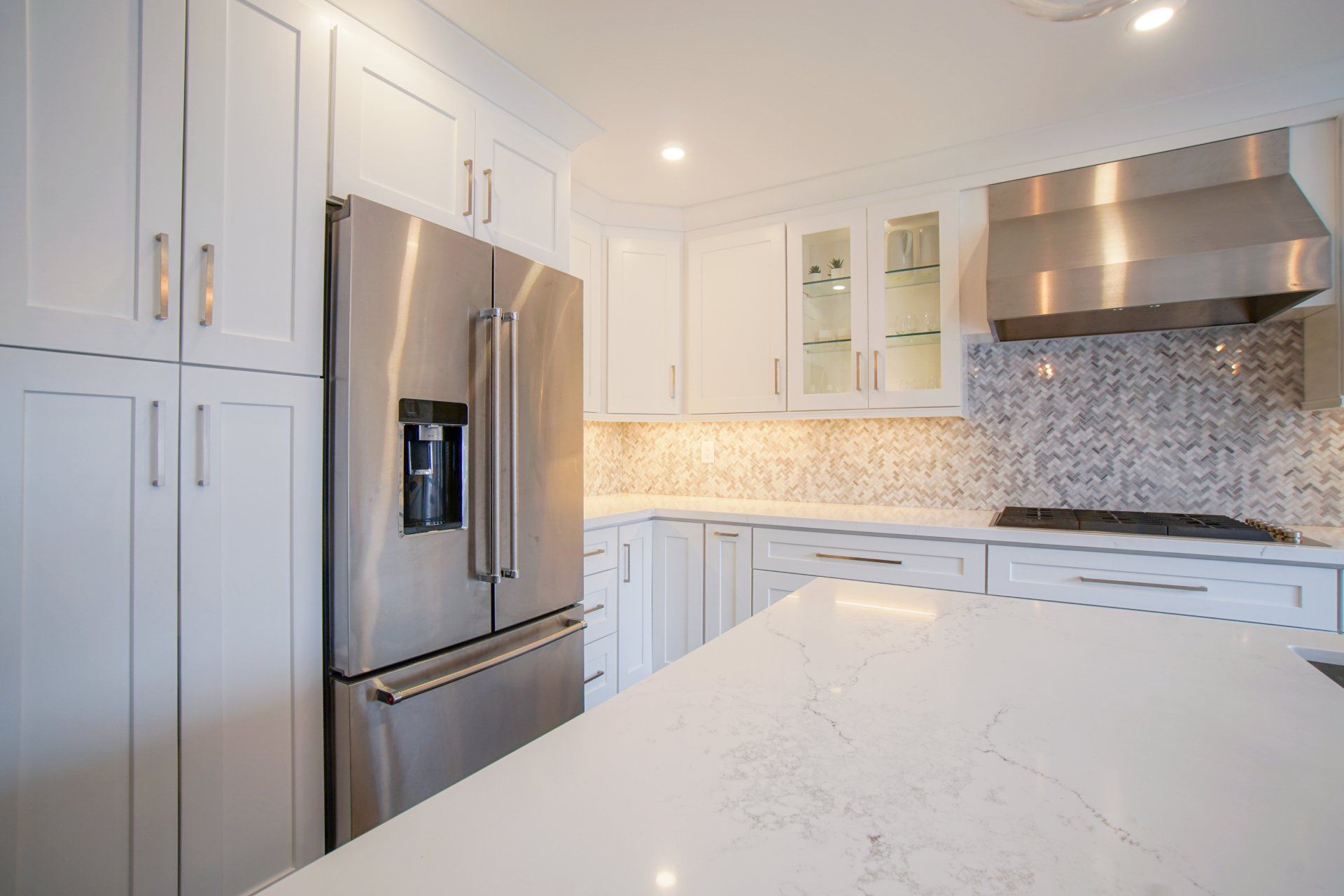 a kitchen with white cabinets , stainless steel appliances , a stove and a refrigerator .