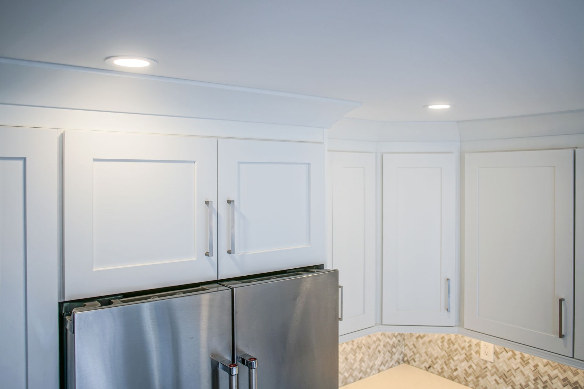 A kitchen with white cabinets and a stainless steel refrigerator.