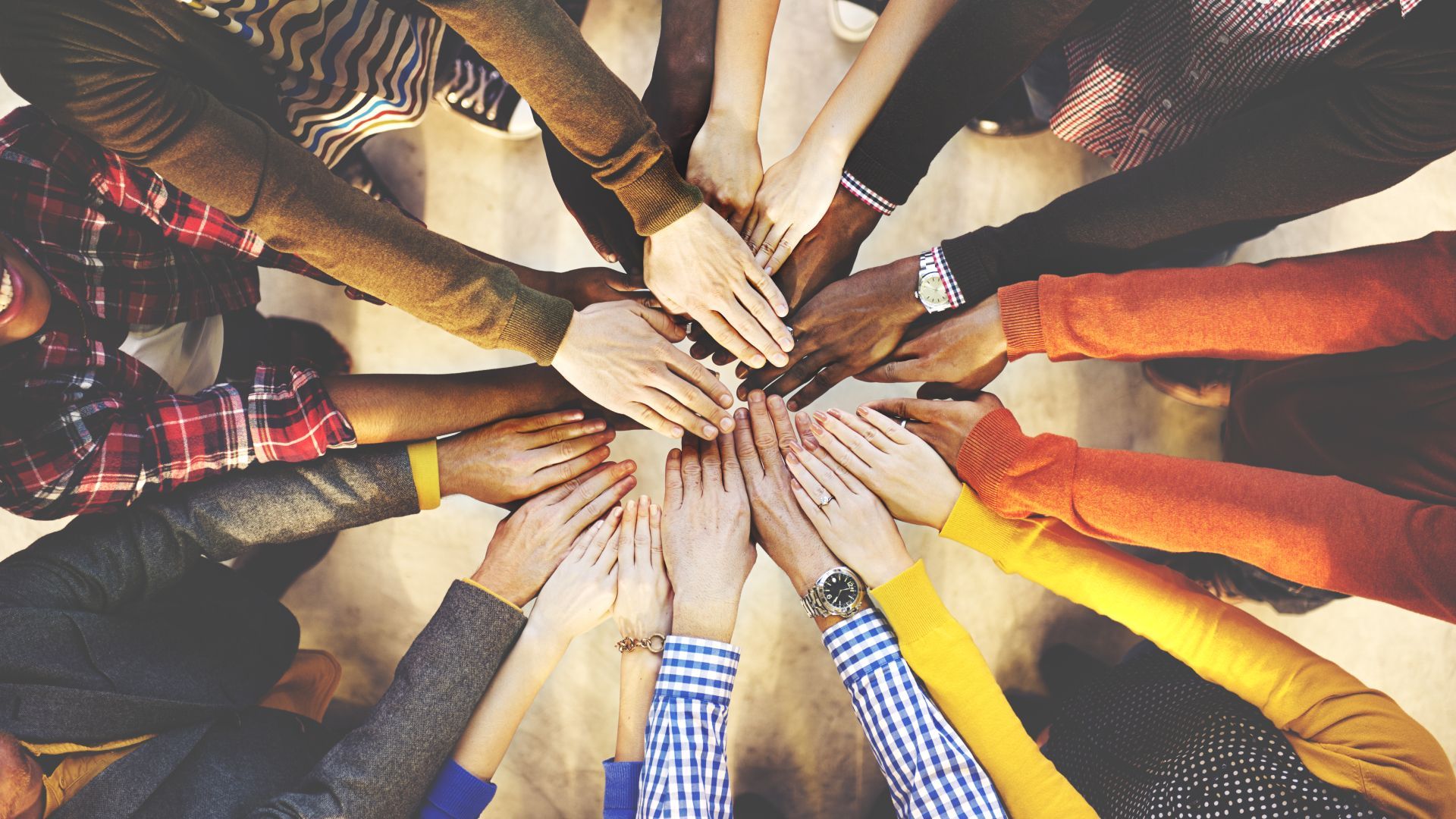 A group of people are putting their hands together in a circle.