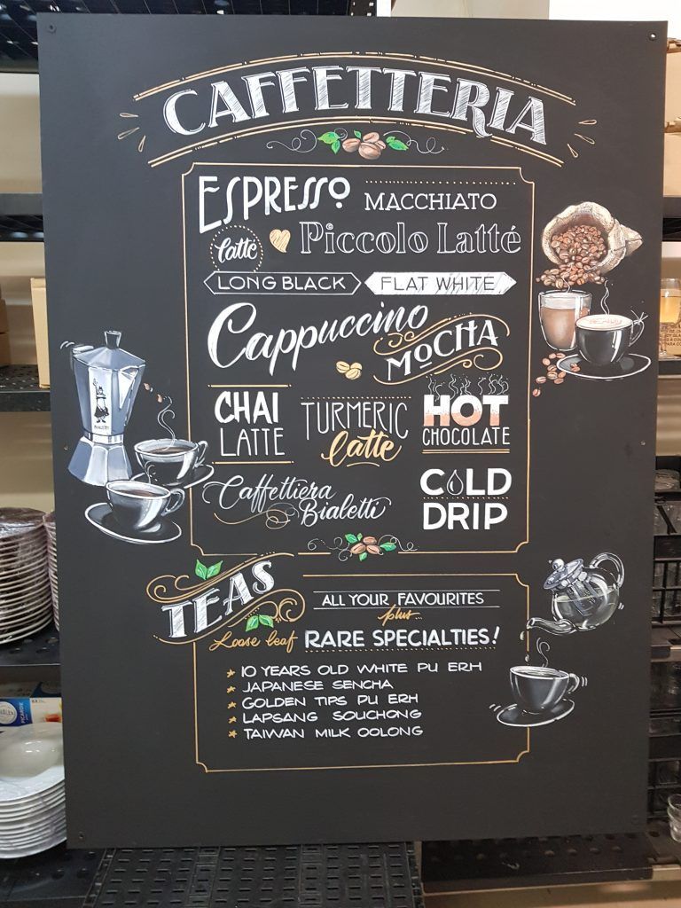 A blackboard with a list of coffee drinks on it.