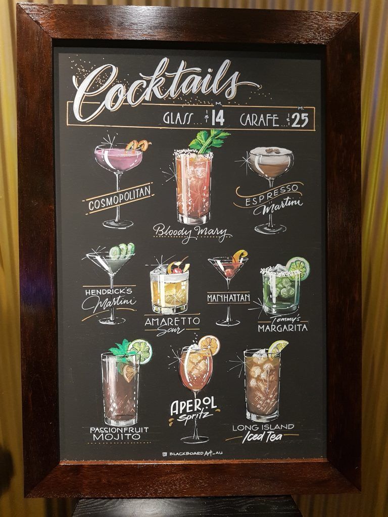 A chalkboard with a list of cocktails on it
