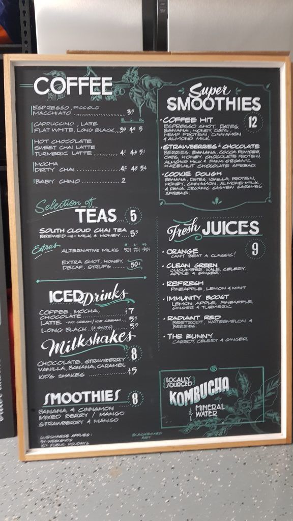 A chalkboard with a menu for coffee and smoothies on it.