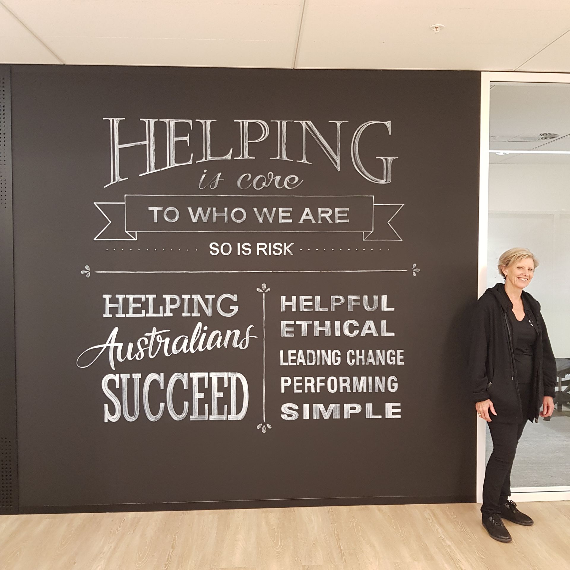 A woman is writing on a blackboard with chalk.